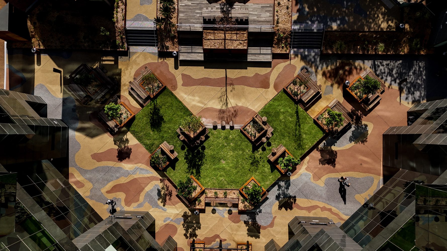 Aerial view of a commercial courtyard with StoneSet resin-bound paving in tan and rust tones surrounding a diamond-shaped lawn