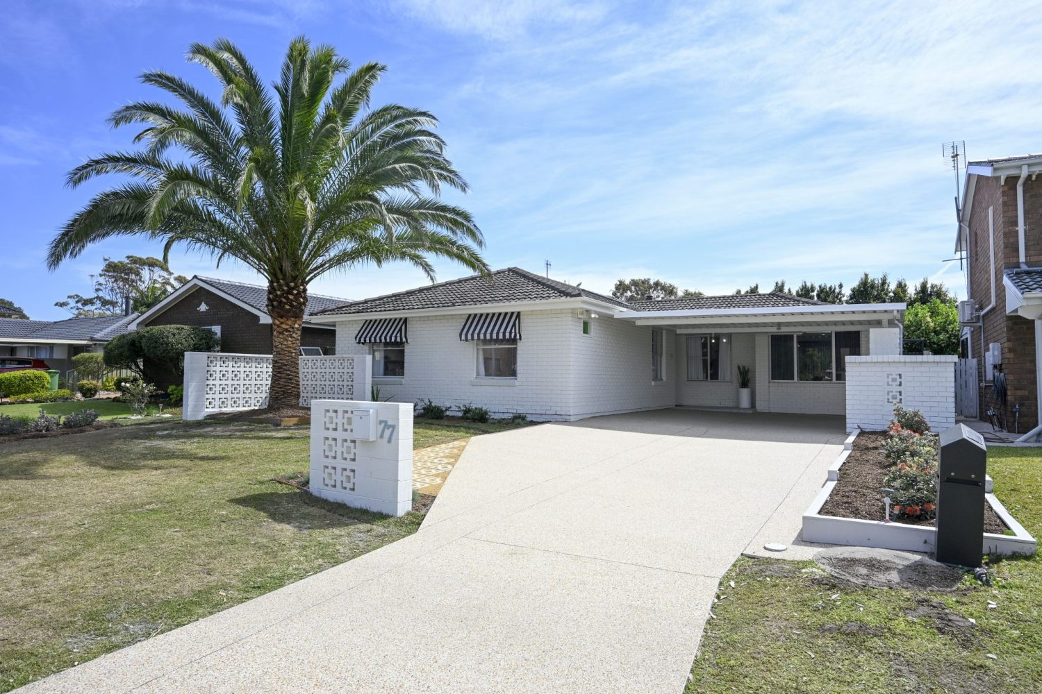 Light-toned StoneSet Palm Springs resin-bound driveway in front of a white coastal home with a palm tree at St Huberts Island
